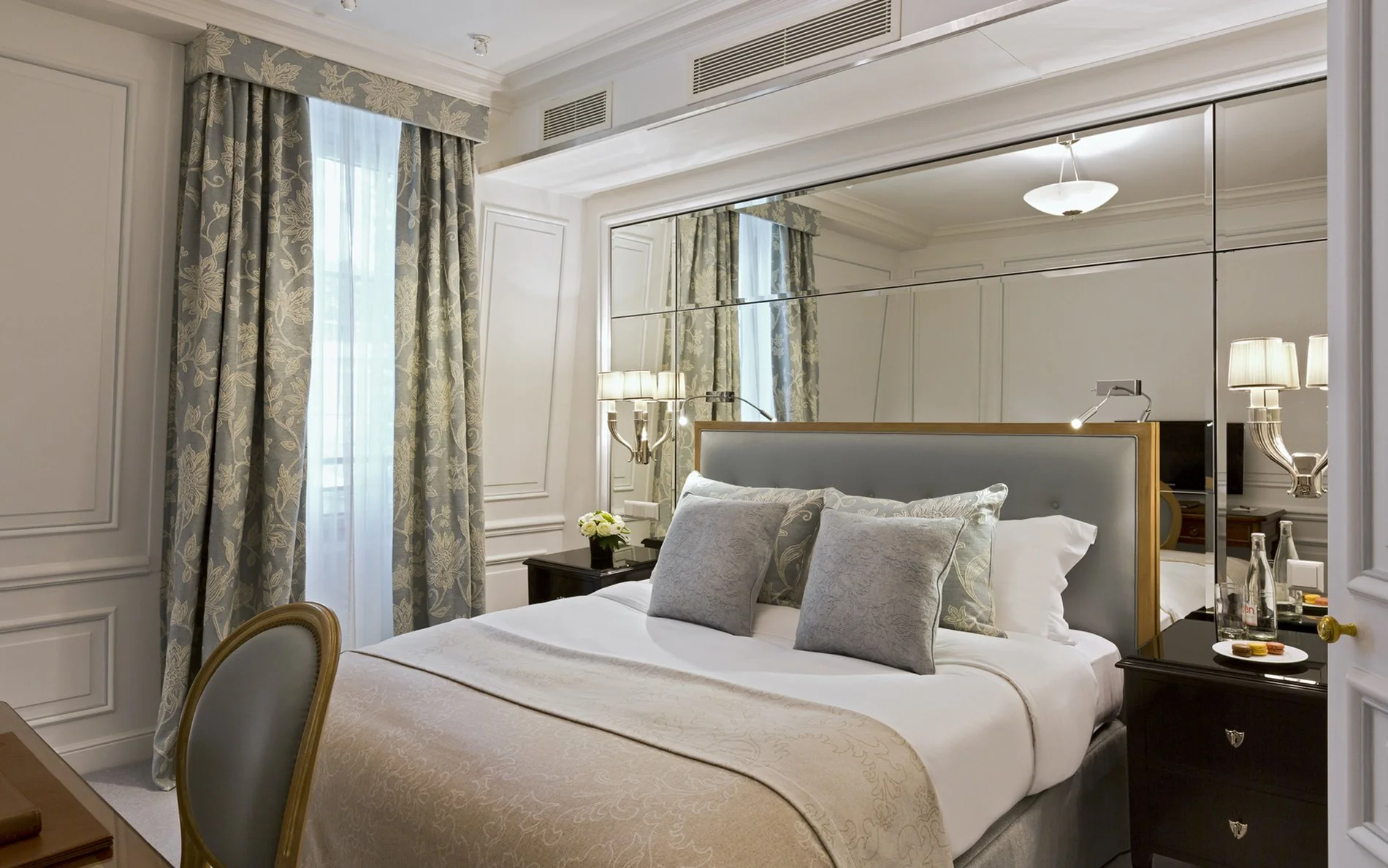 Chambre individuelle de l’Hôtel San Régis à Paris, décoration classique, grands miroirs et lumière naturelle.